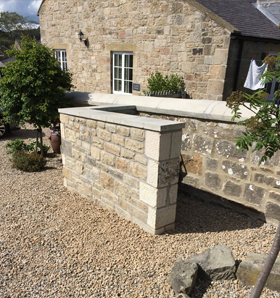 stoned garden wall surrounding house in matching stone build