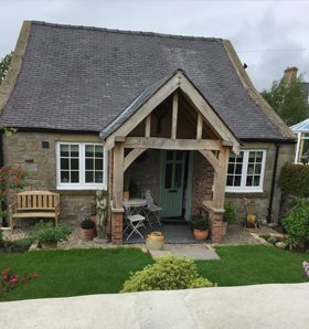 stone cottage with teal front door and green grass out front in garden