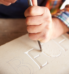 hand carving letters in stone slab for headstone