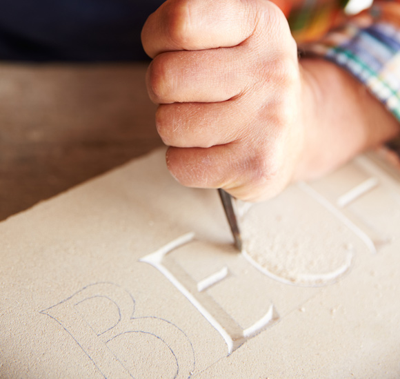 hand carving letters in stone slab for headstone